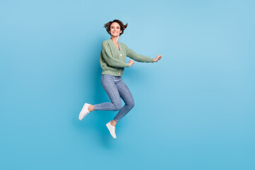 Fototapeta na wymiar Full length photo of sweet cute young lady wear green cardigan jumping high isolated blue color background