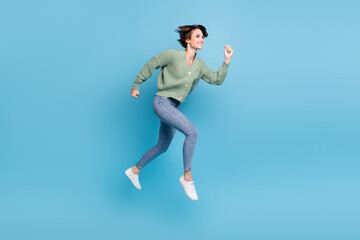 Fototapeta na wymiar Full length photo of funny purposeful young lady wear green cardigan jumping running isolated blue color background