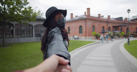 African tourist woman in safety mask leading man. Pov follow me shot