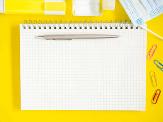 Top view, Flat lay, blank notebook on office yellow workplace tabletop with pen, hand sanitizer...
