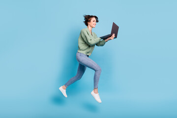 Photo of hurry sweet young woman wear green cardigan jumping running typing modern device isolated...
