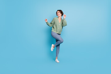 Full length photo of shiny charming young girl dressed green cardigan dancing isolated blue color background