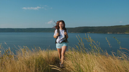 The young woman hiking with backpack along the beautiful coast