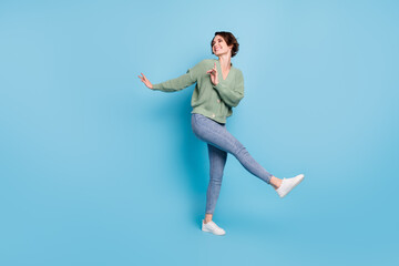 Full length photo of charming pretty young girl dressed green cardigan dancing isolated blue color background