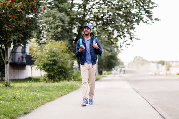 food shipping, profession and people concept - happy smiling indian delivery man with thermal insulated bag and smartphone walking along city street