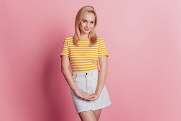 Portrait of shy adorable lady hold hands white smile posing on pink background
