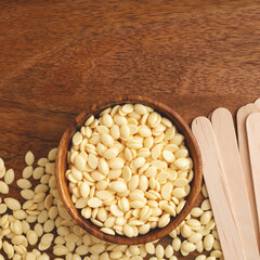 Hair removal wax beans and wooden spatulas. Cosmetics background. Depilation, beauty treatment.