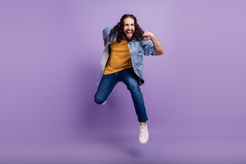 Closeup of crazy man jump fly run wear casual clothes on purple wall
