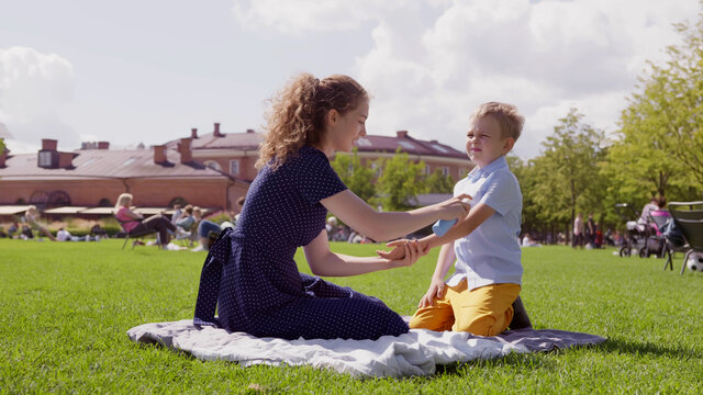 Mother Putting Sunscreen On Little Son In Summer Park