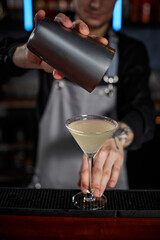 male barman hands is making cocktail with steel shaker