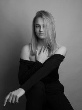 Girl, blonde, shoulder-length hair. Posing in the studio on a light background. Black clothes. Spring summer type. Baby face. Black and white photo