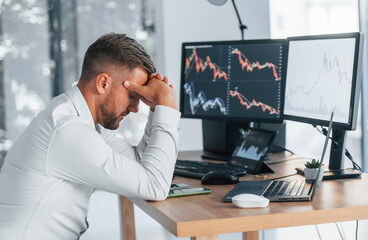 Naklejka premium Risky job. Young businessman in formal clothes is in office with multiple screens