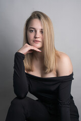 Fototapeta premium Girl, blonde, shoulder-length hair. Posing in the studio on a light background. Black clothes. Spring summer type. Baby face.