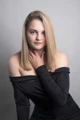 Fototapeta premium Girl, blonde, shoulder-length hair. Posing in the studio on a light background. Black clothes. Spring summer type. Baby face.
