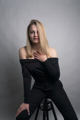 Fototapeta na wymiar Girl, blonde, shoulder-length hair. Posing in the studio on a light background. Black clothes. Spring summer type. Baby face.