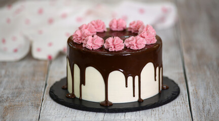 Delicious homemade cake decorated with chocolate and pink cream flowers.