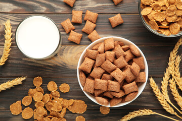 Variety of cereals in blue bowls, quick breakfast and milk on brown wooden background.