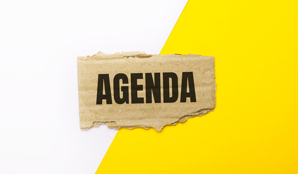 On a white and yellow background, brown torn cardboard with the text AGENDA