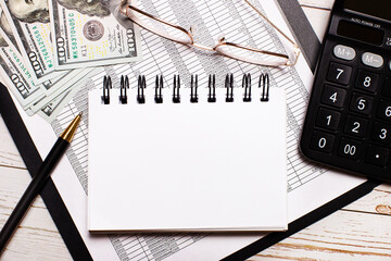 On the office table there is a calculator, a notebook with a place to insert text, a pen, glasses...