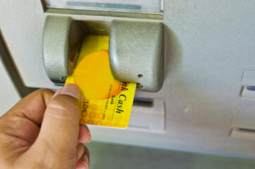 Person inserting ATM cash card in ATM slot. India.