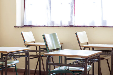Photo of some chairs and tables in a classroom of a nursery school.The photo is shot in horizontal format.