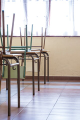 Infant school chairs raised on top of the desks.The photograph is shot in portrait format.