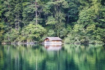 Fototapeta premium Beautiful green lake with a boats house in the forest and mountains