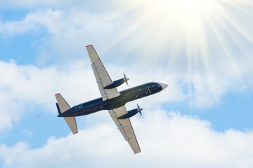 turboprop passenger plane flies in the sky with bright sun.