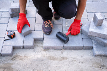 The master in yellow gloves lays paving stones