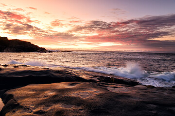 Dawn on the ocean. Splashing waves crashing against the coastal rocks against the backdrop of the rising sun. USA. maine.