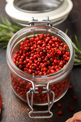 Red Peppercorns in glass jar on wooden table