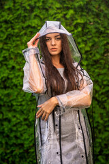 Young beautiful woman in hooded raincoat on rainy day