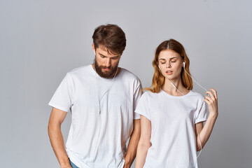 Fototapeta premium man and woman in white t-shirts music in headphones light background