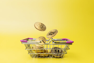 Shopping basket with bitcoins over yellow background
