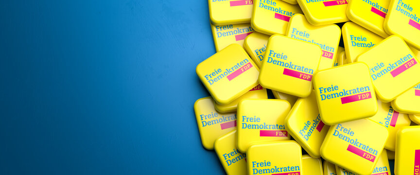 Logos of the liberal German political party FDP on a heap on a table. Copy space. Web banner format.