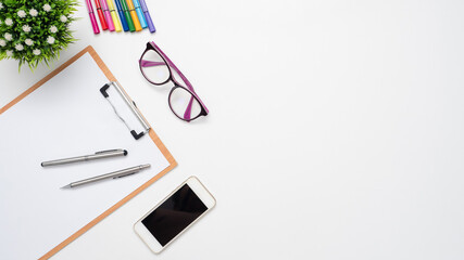 Document board and pen with mobile phone glasses color pen vase on the table top view copy space