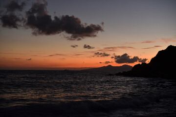 sailing ship from rocky coast to the open sea at dusk