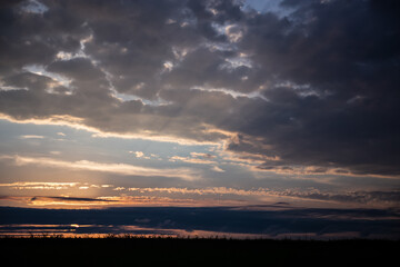 Obraz premium God rays on the forest. The sun's rays shine through the clouds. The power of the sky and a riot of colors. Copy space.