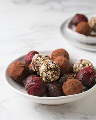 Chocolate candies. Delicious dessert on a light background. Truffles with waffle crumbs, with cocoa. Sweets on a white plate. Macro photography of sweets.