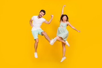 Fototapeta na wymiar Photo of sporty champion couple jump celebrate victory wear casual outfit isolated yellow color background