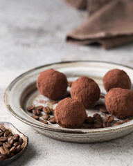 Chocolate candies. Delicious dessert on a light background. Coffee truffles. Sweets on a white plate. Macro photography of sweets.