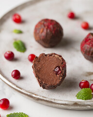 Chocolate candies. Delicious dessert on a light background. Cranberry truffles made of dark chocolate. Sweets on a white plate. Macro photography of sweets. .Candy Cut