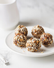Chocolate candies. Delicious dessert on a light background. Truffles with waffle crumbs. Sweets on a white plate. Macro photography of sweets.