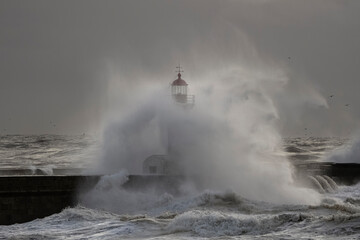 Fototapeta na wymiar Spray from big breaking waves over lighthouse