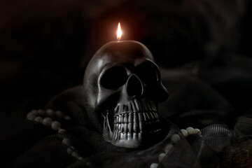 Black skull candle on black background. Halloween concept, mysticism, the afterlife.