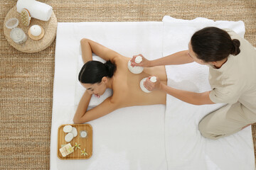 Young woman receiving herbal bag massage in spa salon, top view