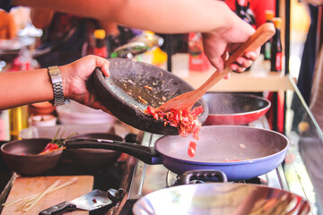 Pouring food ingredients on frying pan.