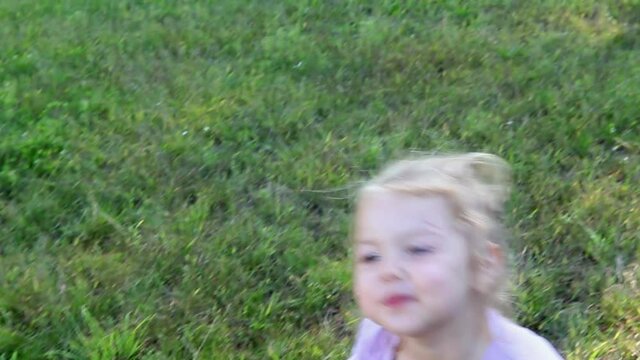 Cute little girl 3 years old with curly hair gathered in a ponytail on a green natural background