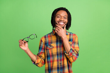 Photo of pretty thoughtful dark skin man wear plaid shirt smiling holding spectacles arm chin...