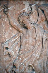 An old, weathered sandstone sculpture of a male angel. 